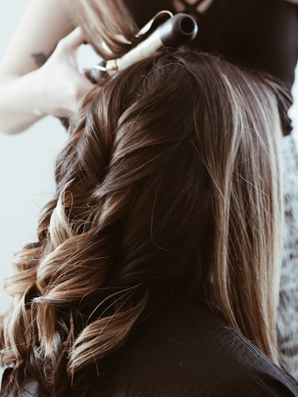 A stylist shaping curls with a curling iron